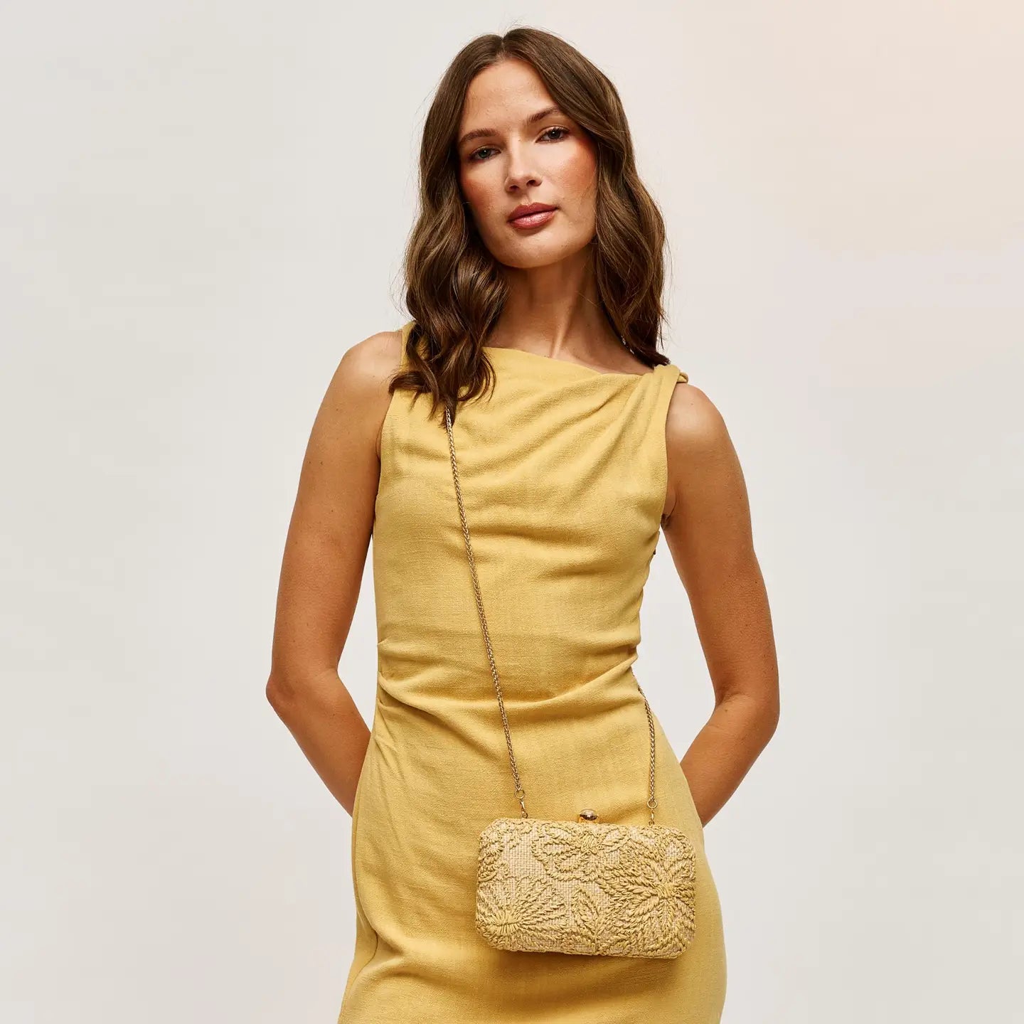 straw natural woven handbag clutch on a woman wearing a yellow dress